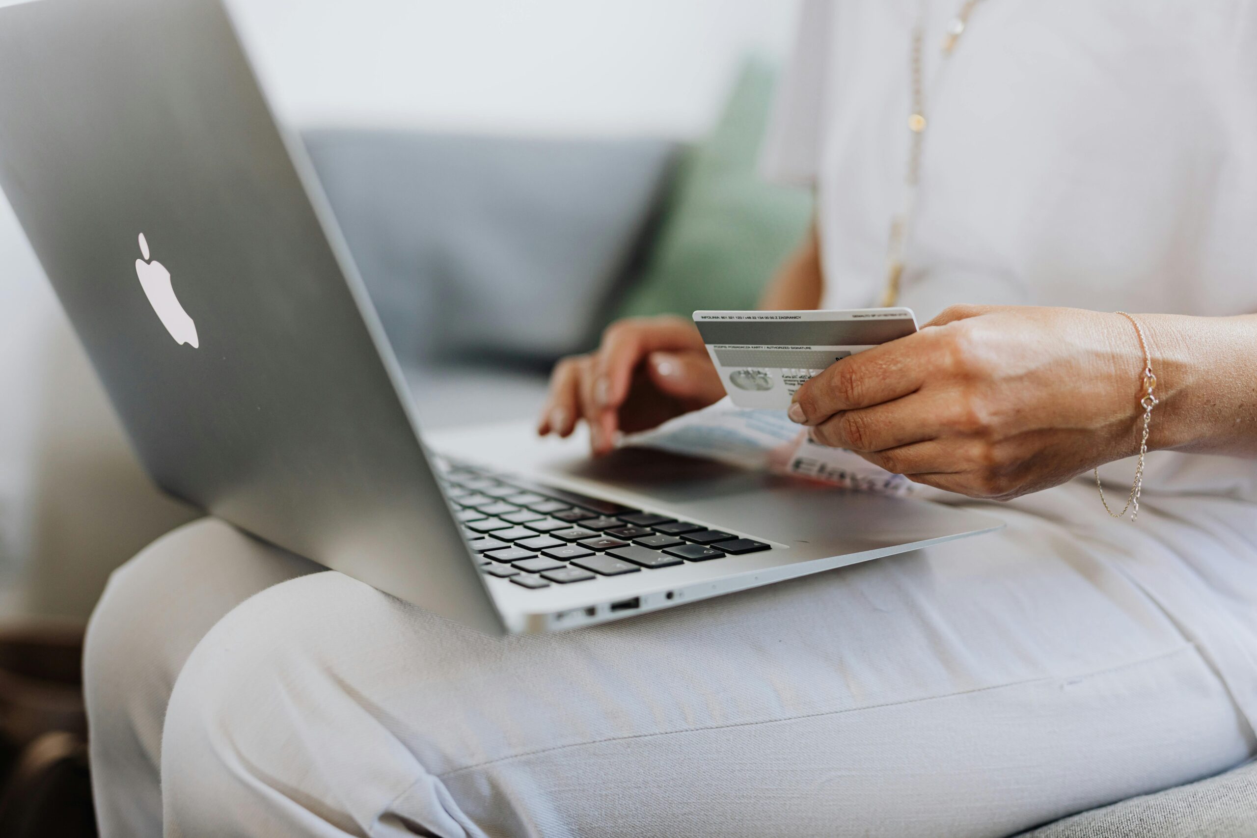 computer on person's lap, credit card in hands as if to shop online